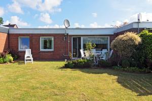 a brick house with a lawn in front of it at Bungalow Tilla in Norddeich