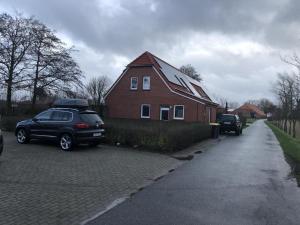 una casa con dos coches estacionados frente a ella en Fewo Imke en Norden