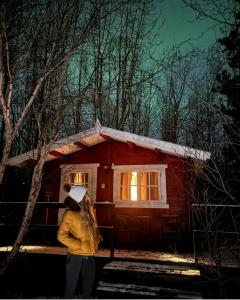 a woman standing in front of a small cabin at Bakkakot 2 - Cozy Cabins in the Woods in Akureyri