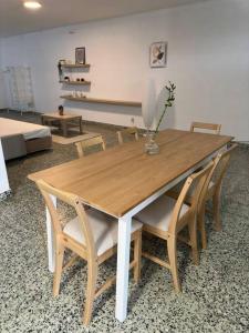 einen Holztisch mit Stühlen und eine Vase mit einer Blume darauf in der Unterkunft Apartamento Estudio Com Entrada Privada in Arrentela