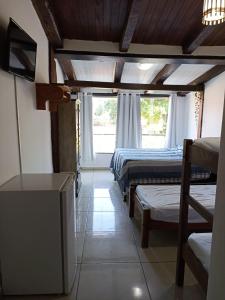 a room with two beds and a tv and a window at Pousada Portal da Mucugê in Porto Seguro