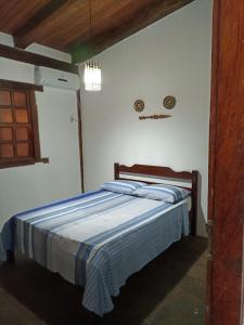 a bedroom with a bed with a blue striped blanket at Pousada Portal da Mucugê in Porto Seguro