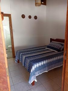 a bedroom with a bed with a blue and white blanket at Pousada Portal da Mucugê in Porto Seguro
