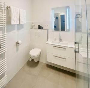 uma casa de banho branca com um WC e um lavatório em Traumhafter Ostsee-Ausblick, FeWo direkt am Strand em Fehmarn