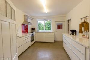 a large kitchen with white cabinets and a window at Ferienhaus Rote Sau in Herrentierbach