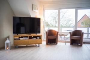 a living room with two chairs and a flat screen tv at Captain´s Suite in Gollendorf – mit Kaminofen in Gollendorf