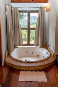 a bath tub in a room with a window at Pousada Serra Vista in Gonçalves