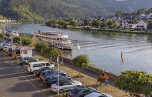 a row of cars parked next to a river with a boat at FerienSchlösschen Zell in Zell an der Mosel
