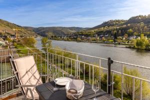 a table and a chair on a balcony overlooking a river at Ferienhaus Moselherz in Merl