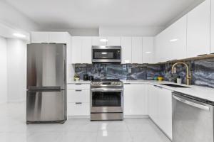 a kitchen with white cabinets and a stainless steel refrigerator at Pristine 3 Beds 2 Washroom Guest Suite in Surrey