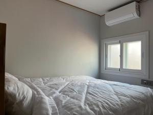 a white bed in a room with a window at Clara House in Seoul