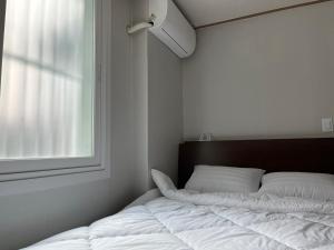 a white bed in a room with a window at Clara House in Seoul
