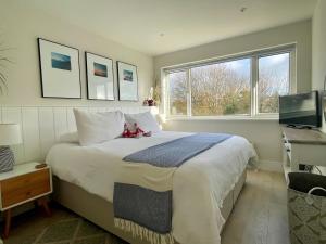 a bedroom with a large white bed with a window at Seafeathers - Luxury Holiday Home with Sea Views in Overcombe