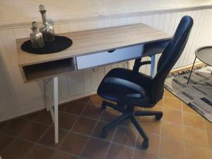a desk with a black chair in front of it at Koselig rom med stue i Bodø sentrum in Bodø