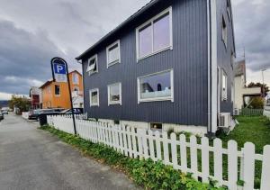 a blue house with a white fence next to a street at Koselig rom med stue i Bodø sentrum in Bodø