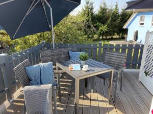 einen Holztisch und Stühle mit Sonnenschirm auf einer Terrasse in der Unterkunft Ferienwohnung de olle Leive in Born in Born