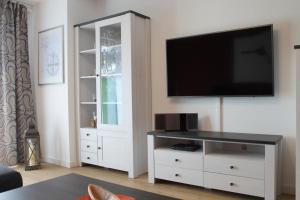 a living room with a white entertainment center with a flat screen tv at Ferienwohnung de Windroos in Born