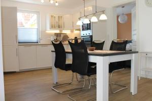 a kitchen with a table and black chairs at Ferienwohnung de Windroos in Born