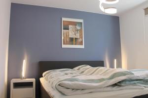 a bedroom with a bed with a blue wall at Ferienwohnung de Windroos in Born