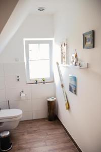 a white bathroom with a toilet and a window at Ferienwohnung Ostwind in Born in Born