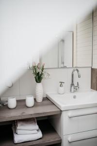 a white kitchen with a sink and a vase of flowers at Apartments Kirsebek in Kappeln