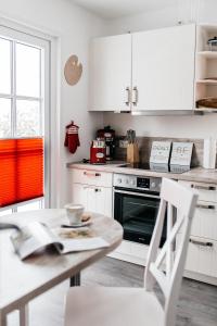 a kitchen with white cabinets and a table at Ferienhaus Kleiner Onkel in Grödersby
