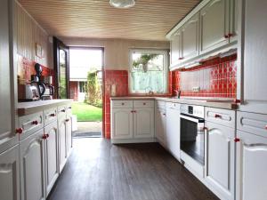a kitchen with white cabinets and red tile at Amrum in Kappeln