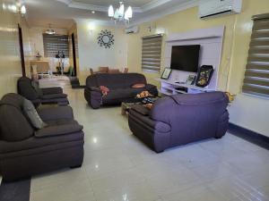 uma sala de estar com dois sofás e uma televisão em Entire 3 Bedroom Bungalow - Home away from home em Lagos