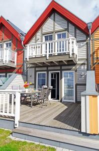 a house with a wooden deck with a table and chairs at Misfit in Olpenitz