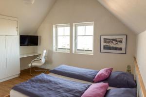 a bedroom with two beds and a tv and two windows at Hus im Lee un Luv in Olpenitz