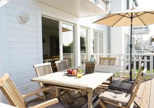 a wooden table and chairs on a porch with an umbrella at The Beach House in Olpenitz
