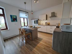 a kitchen with white cabinets and a table and chairs at Naturnahes Ostsee und Schlei Erlebnis im Landhaus Grüne Oase an der Geltinger Bucht in Stangheck