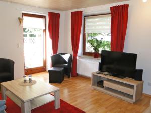 a living room with a television and red curtains at Skrey's To Hus in Kappeln