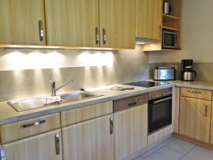 a kitchen with wooden cabinets and a sink and a microwave at Skrey's To Hus in Kappeln
