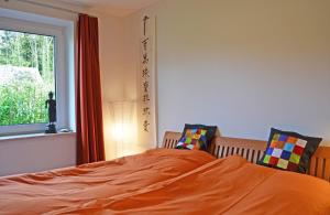 a bedroom with a bed with orange sheets and a window at Schleiglanz in Ulsnis
