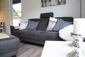 a living room with a grey couch with pillows at Schmidt's Huus in Damp