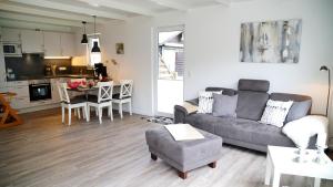 a living room with a gray couch and a kitchen at Schmidt's Huus in Damp