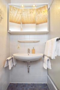 ein Badezimmer mit einem Waschbecken, einem Spiegel und Handtüchern in der Unterkunft Gut Fallenstein in Bayerisch Gmain