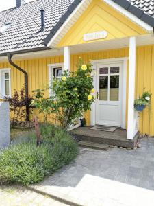uma casa amarela com uma porta branca e um alpendre em Pippilotta em Kronsgaard