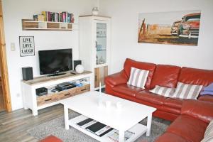 uma sala de estar com um sofá de couro vermelho e uma televisão em Pippilotta em Kronsgaard