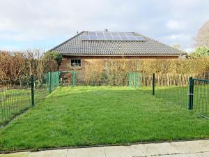 a house with a yard with a fence and a house with solar panels at Strandgold in Kronsgaard