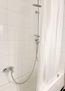 a shower with a shower curtain next to a tub at Strandgold in Kronsgaard