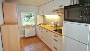 uma cozinha com um frigorífico branco e um micro-ondas em Geel Hus em Brodersby