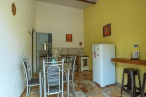 a kitchen with a table with chairs and a refrigerator at Vyzuh Guest House in Vale do Capao