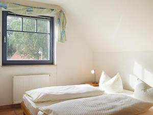 a white bedroom with a bed and a window at Haus Komoran Wohnung 3 in Prerow
