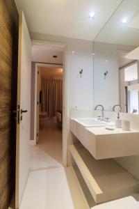 Baño blanco con lavabo y espejo en Apartment Ocean View II, en Río de Janeiro