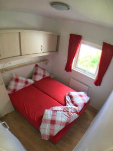ein rotes Bett in einem kleinen Zimmer mit Fenster in der Unterkunft "OSLO" - Haus am See mit Sandstrand nahe Rhein-Main und Spessart in Kahl am Main
