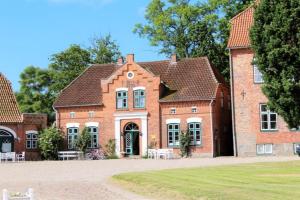 a red brick building with a tree in front of it at FerienGut Gaarz - Kavaliershaus 17 in Göhl