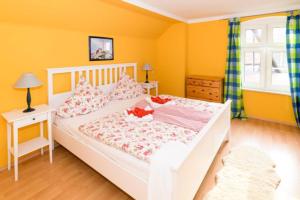 a bedroom with a white bed and yellow walls at FerienGut Gaarz - Kavaliershaus 17 in Göhl