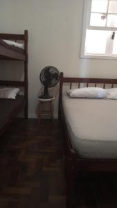 a bedroom with two beds and a chair and a window at Apto Central Barra de Imbé in Imbé